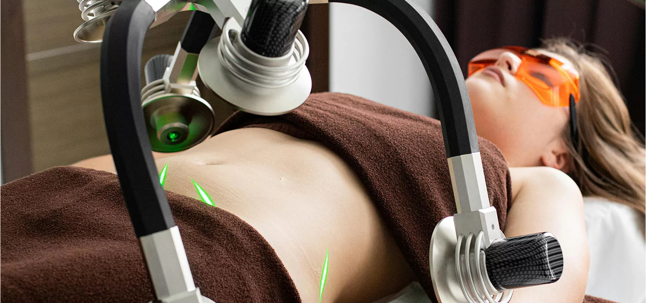 A woman receiving a fat reduction treatment on her stomach in a clinical setting.